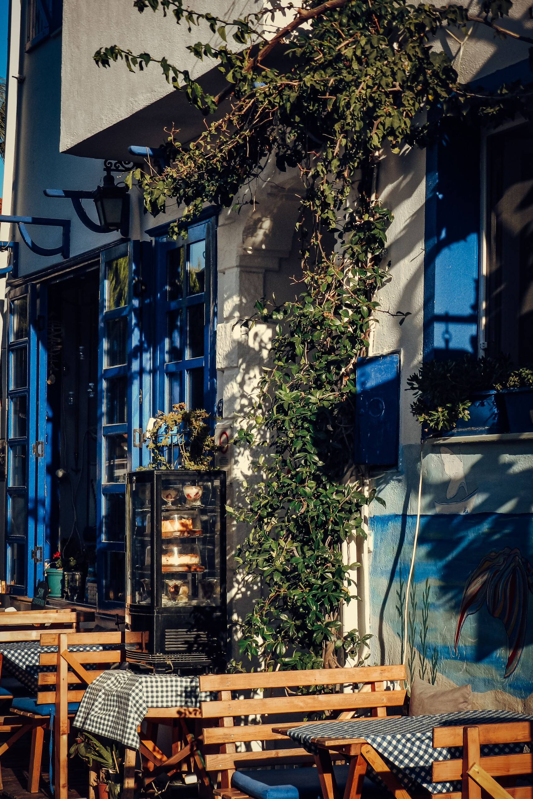 A café terrace with blue shutters and a pastry case in old Larnaca