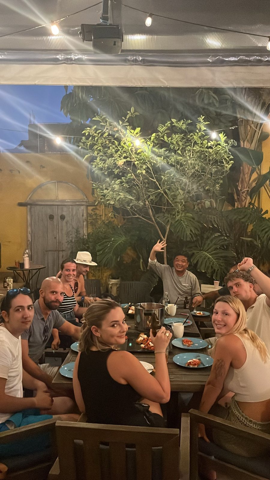 Guests sharing the long table in Le Mat Hostel's courtyard in the evening