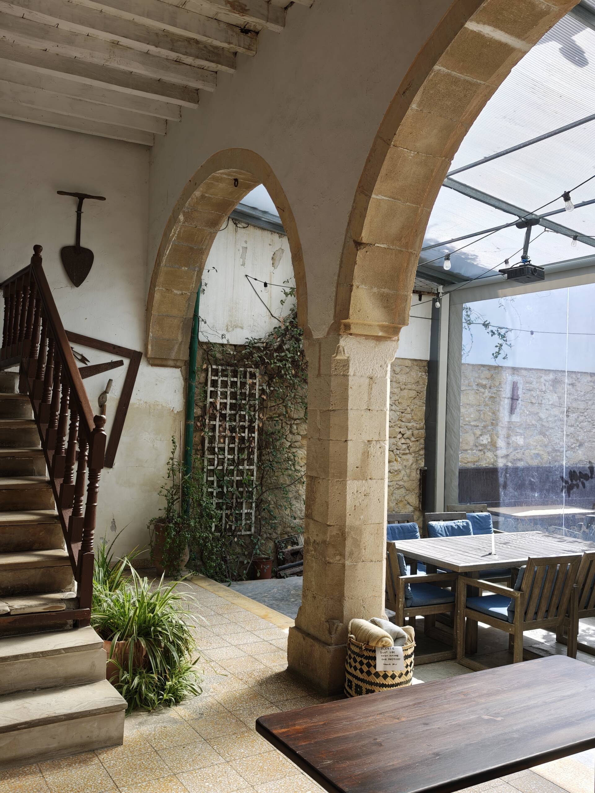 The covered stone courtyard at Le Mat Hostel, with an old arch, communal dining table, and seating